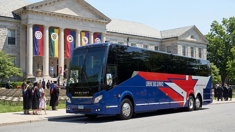 Lorenz Bus Service Prevost motorcoach parked in front of a university Commencement Hall during a graduation ceremony