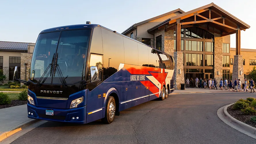 Lorenz Bus Service Prevost motorcoach parked outside a venue entrance as passengers board at sunset