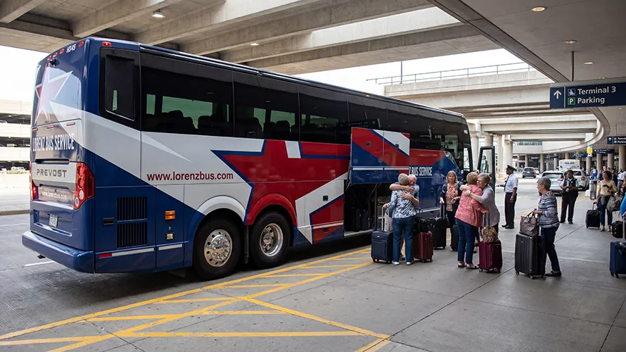 Lorenz Bus Service Prevost motorcoach at an airport terminal as passengers with luggage board and greet one another curbside