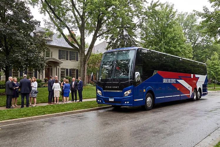 Lorenz Bus Service Prevost charter coach picking up a group of formally dressed passengers outside a residential home
