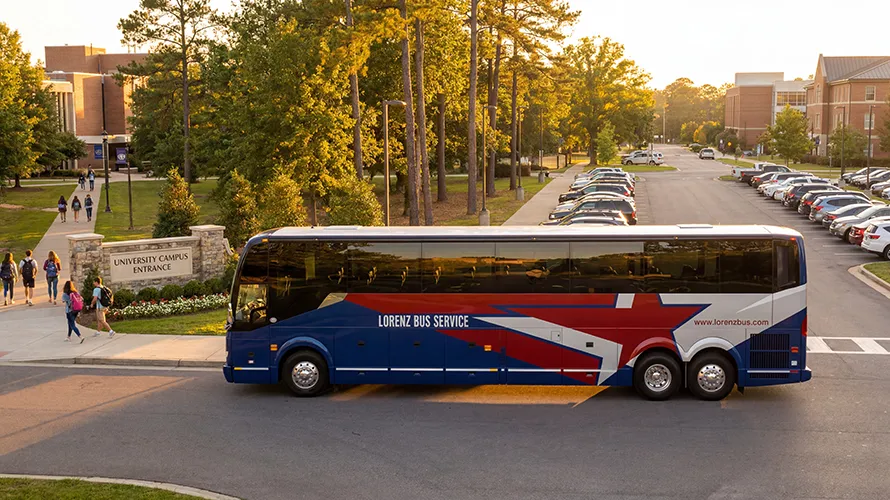 Lorenz Bus Service motorcoach parked at a university campus entrance with students walking nearby