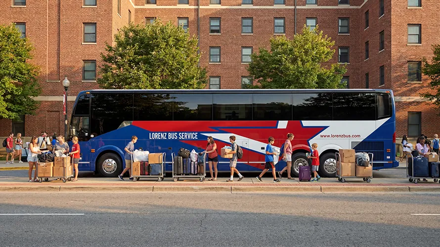 Students and families unloading luggage and boxes from a Lorenz Bus Service coach outside a university residence hall