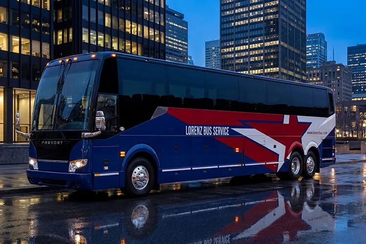 Lorenz Bus Service Prevost motorcoach parked in a downtown city setting at dusk, reflecting on wet pavement