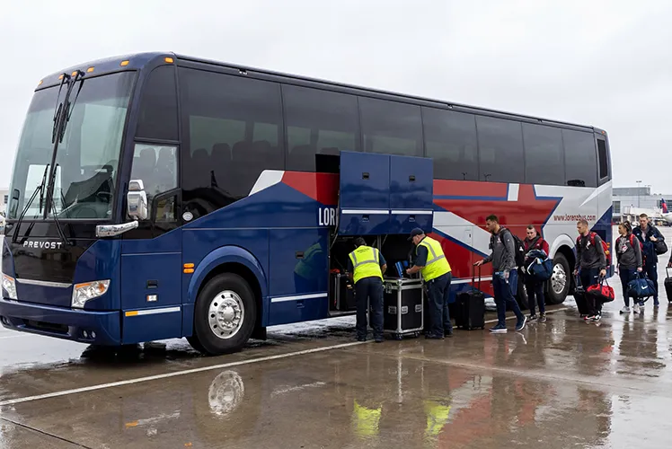 Lorenz Bus Service Prevost charter coach loading athletic team equipment and luggage at an airport tarmac