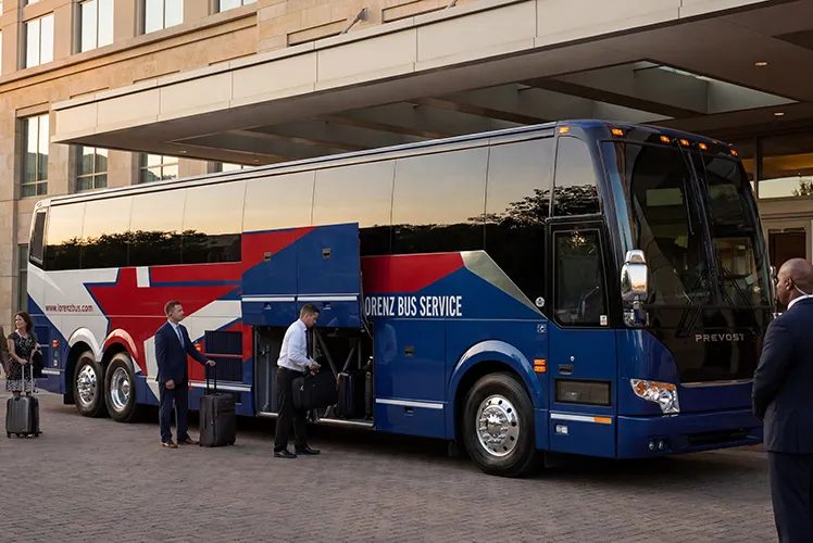 Passengers loading luggage into a Lorenz Bus Service Prevost coach outside a hotel