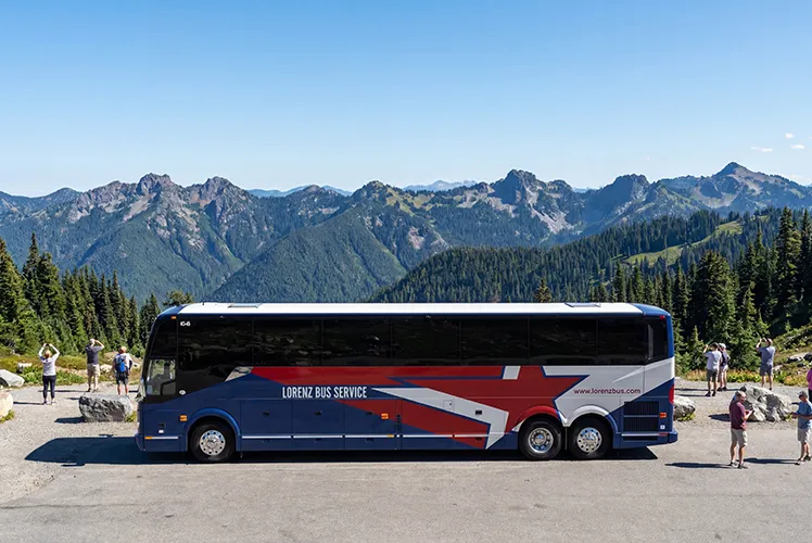 Lorenz Bus Service charter coach parked at a mountain overlook with passengers exploring the scenic surroundings