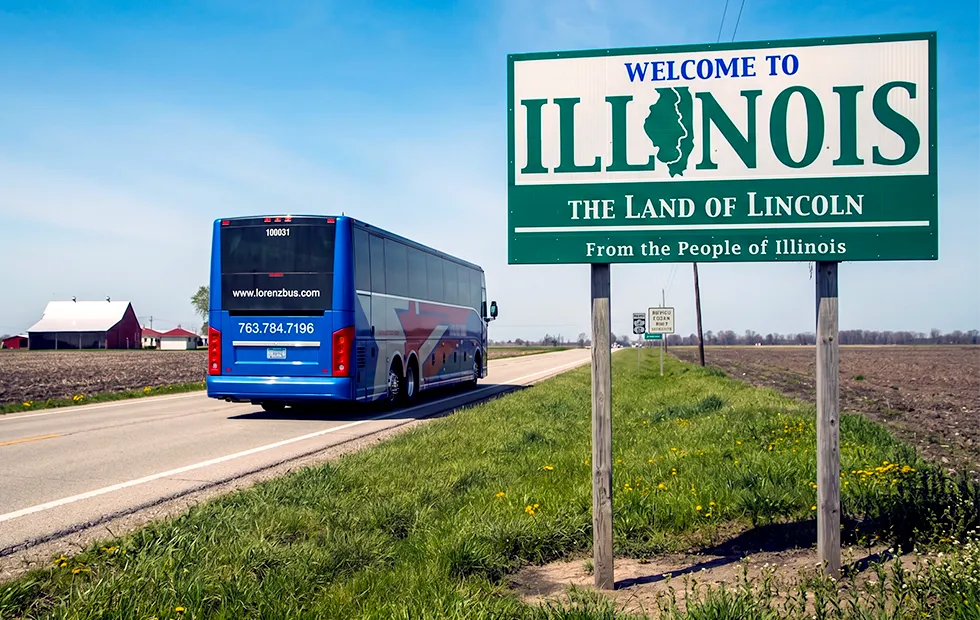 Lorenz Bus Service motorcoach passing a Welcome to Illinois — The Land of Lincoln highway sign on a rural road