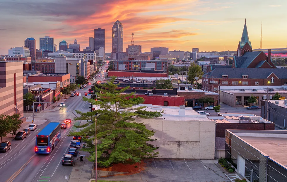 Aerial view of Des Moines, Iowa skyline at sunset with a charter bus traveling along a downtown street