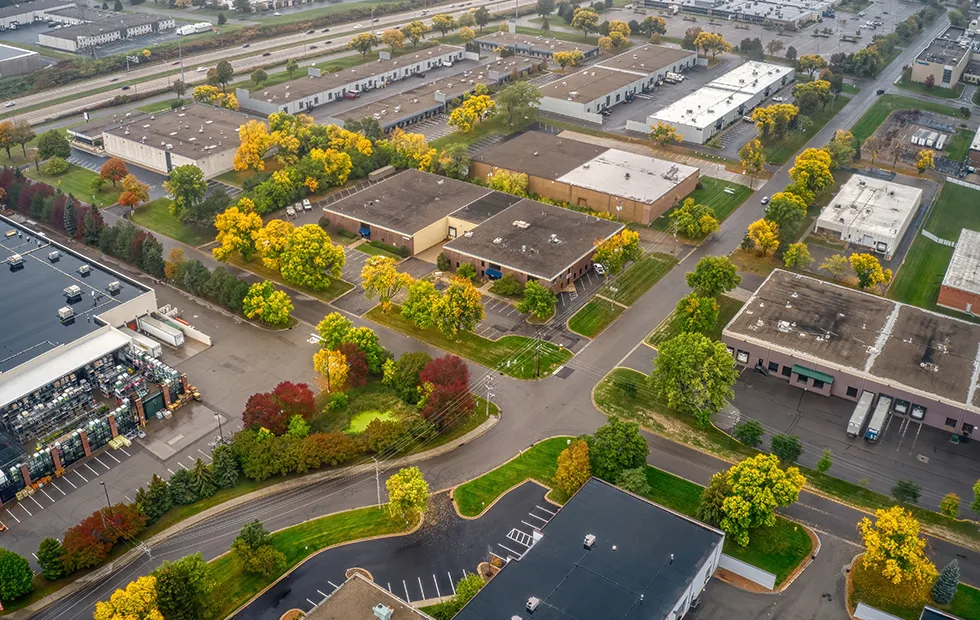 Aerial view of a Midwest commercial and industrial district with warehouses, parking lots, and fall-colored trees
