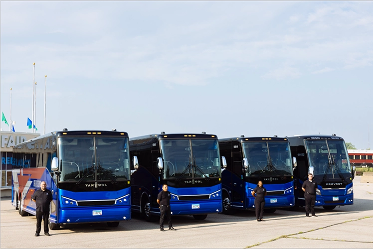 Four Lorenz Bus Service coaches—Van Hool and Prevost models—lined up outdoors with uniformed drivers standing in front of each bus